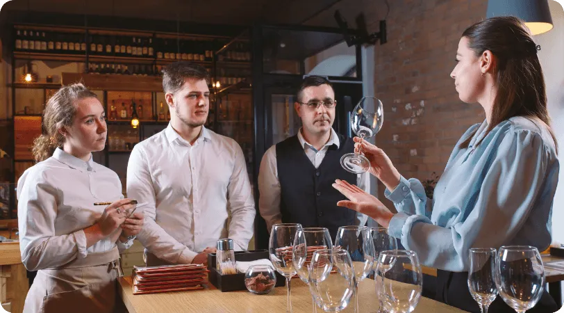 Restaurant staff watching a trainer inspect a wine glass